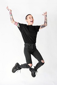 Tattooed model in black t shirt and jeans jumping