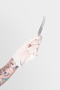 Tattooed hand in a white glove holding a curved tweezers