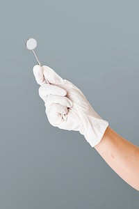 Dentist&#39;s hand in white glove holding a mouth mirror