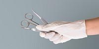 Gloved hand holding stainless steel medical instruments