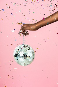 Woman holding a shiny silver disco ball and confetti 