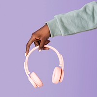 Hand holding pink headphones with purple background