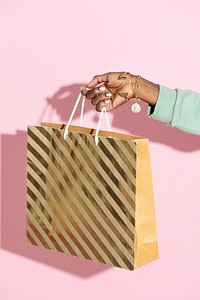 Woman carrying a shopping bag against a pink background