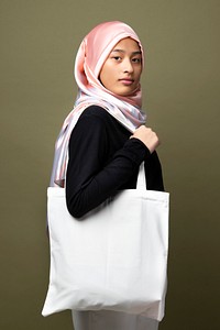 Muslim woman carrying a white tote bag