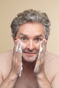 Senior man using facial foam cleanser to wash his face