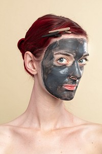 Beautiful woman wearing an activated black charcoal mask for facial treatment