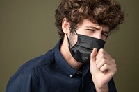 Young Caucasian man wearing a black face mask coughing