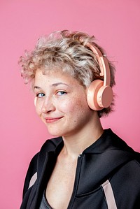 Studio portrait of a sporty cute blonde girl wearing black hoodie and headphones