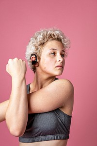 Young active woman wearing a bluetooth headset while stretching