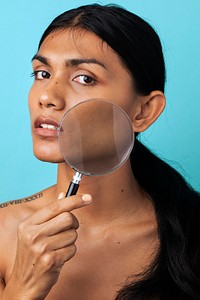 Woman using a magnifying glass to check her skin