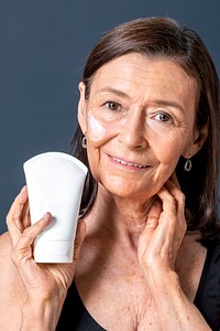 Senior woman holding a white face cream tube