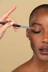 Makeup artist applying eye shadow on a black woman