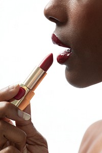 Black woman applying red lipstick on her lips