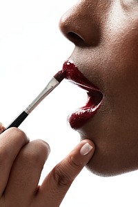 Black woman applying red lipstick 