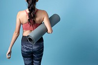 Back view portrait of sportive woman holding a yoga mat