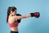 Sportive woman punching on blue background