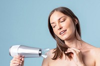 Young woman blow drying her hair 