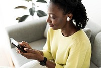 Woman wearing wireless earbuds and using a mobile phone