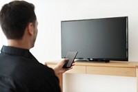 Man turning on smart TV with his smartphone