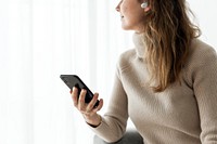 Woman wearing wireless earbuds and using a mobile phone