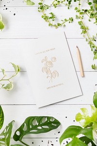 Paper mockup psd on wooden table with plants flat lay