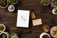 Business card mockup psd on wooden table with plants flat lay