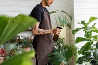 Small business worker misting plants with a water spray