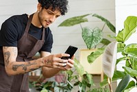 Plant shop worker takes a photo of potted plants