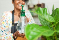 Woman misting plants with a water spray at a plant shop