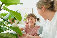 Happy little girl and mom at home with indoor plants