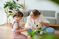 Kid with mom watering potted plants at home