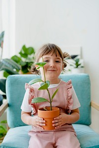 Cute girl kid holding potted plants at home