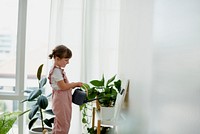 Cute little girl watering plants at home