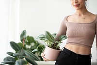 Asian woman plant parent holding potted houseplant