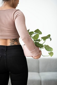 Tattooed millennial plant parent holding potted houseplant