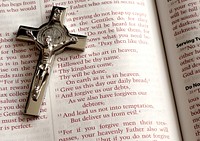 A crucifix on an open Bible showing the Lord's prayer (Matthew 6:9–13). Original public domain image from Wikimedia Commons