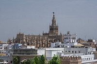 Cathedral, "Giralda", and some roofs, as seen from the "Torre del Oro", Seville, Spain. Original public domain image from <a href="https://commons.wikimedia.org/wiki/File:The_cathedral_and_some_roofs_over_Seville_Spain.jpg" target="_blank" rel="noopener noreferrer nofollow">Wikimedia Commons</a>