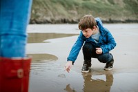 Little boy pointing at jellyfish at the beach with not all classrooms have four walls text