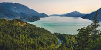 A bend in a road cutting through a dense forest on the shore of a lake. Original public domain image from Wikimedia Commons