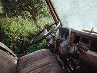 Interior shot of rusty old vehicle with worn seats parked near trees. Original public domain image from <a href="https://commons.wikimedia.org/wiki/File:Rusty_old_vehicle_with_worn_seats_(Unsplash).jpg" target="_blank" rel="noopener noreferrer nofollow">Wikimedia Commons</a>