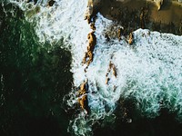 Drone view of the ocean washing on the cliffs at Corona Del Mar. Original public domain image from <a href="https://commons.wikimedia.org/wiki/File:Up_from_Above_(Unsplash).jpg" target="_blank" rel="noopener noreferrer nofollow">Wikimedia Commons</a>
