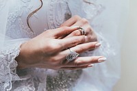 Texas bride touches her wedding ring on finger in front of white lace wedding dress. Original public domain image from Wikimedia Commons