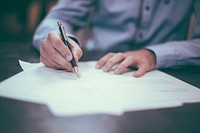 A man in a shirt writing on printed sheets of paper. Original public domain image from Wikimedia Commons