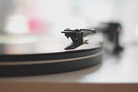 A blurry close-up of a turntable needle. Original public domain image from <a href="https://commons.wikimedia.org/wiki/File:Spins_(Unsplash).jpg" target="_blank" rel="noopener noreferrer nofollow">Wikimedia Commons</a>