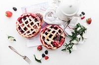 An overhead shot of strawberry and blackberry pies next to a white coffee pot and a bunch of flowers. Original public domain image from <a href="https://commons.wikimedia.org/wiki/File:Top_view_of_fruit_pies_and_a_coffee_pot_(Unsplash).jpg" target="_blank" rel="noopener noreferrer nofollow">Wikimedia Commons</a>