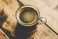 A cup of black coffee on a wooden table. Original public domain image from Wikimedia Commons