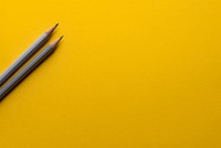 Two gray pencils on a yellow surface. Original public domain image from Wikimedia Commons