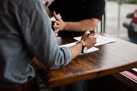 Two people discussing business over a table with documents. Original public domain image from Wikimedia Commons