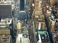 Drone view of the rooftops of buildings and the busy New York City streets. Original public domain image from <a href="https://commons.wikimedia.org/wiki/File:Empire_State_Building,_New_York,_United_States_(Unsplash).jpg" target="_blank" rel="noopener noreferrer nofollow">Wikimedia Commons</a>
