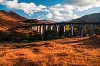 A concrete viaduct running through orange hilly grasslands on a sunny afternoon. Original public domain image from <a href="https://commons.wikimedia.org/wiki/File:Viaduct_in_the_autumn_(Unsplash).jpg" target="_blank" rel="noopener noreferrer nofollow">Wikimedia Commons</a>
